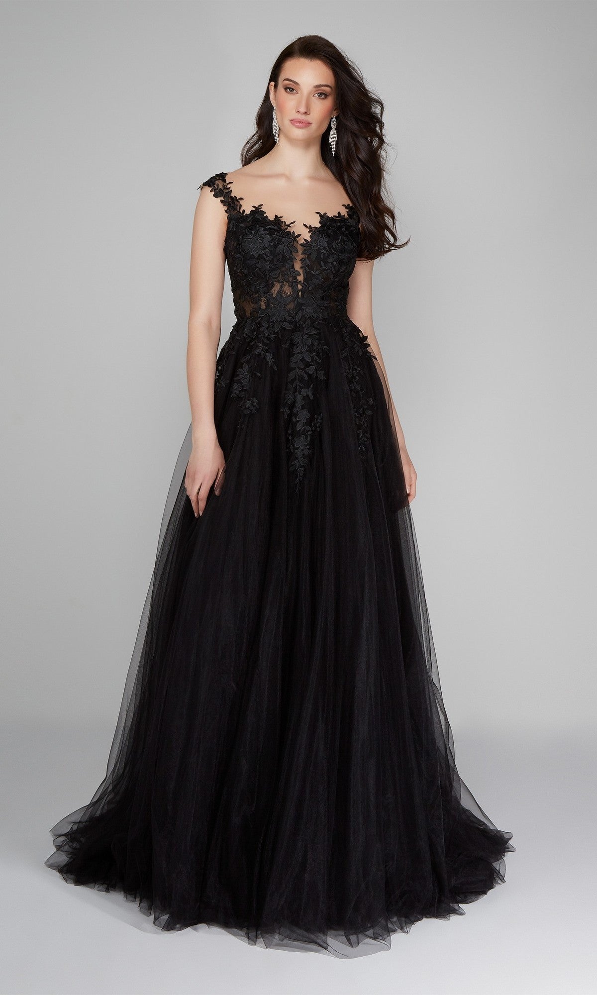 A woman models the Alyce 5090 long formal dress in black, featuring lace embroidery on the bodice, cap sleeves, and an elegant floor-length A-line tulle skirt, posed against a plain gray background.